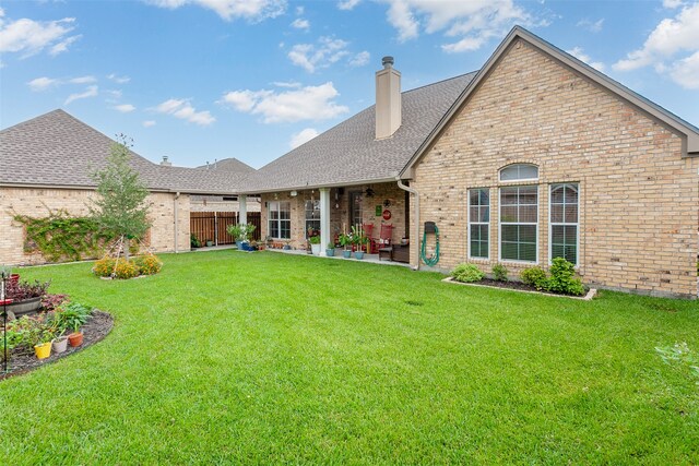 rear view of property featuring a yard and a patio area