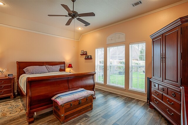 bedroom featuring dark wood-type flooring, multiple windows, ceiling fan, and ornamental molding