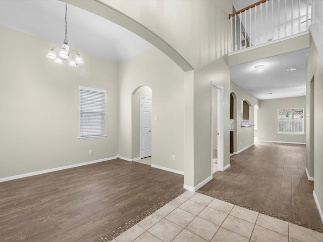 entryway with light hardwood / wood-style flooring, a towering ceiling, and a chandelier