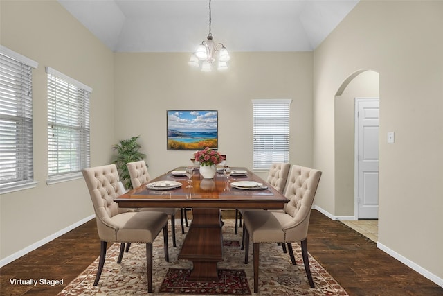 dining space featuring dark hardwood / wood-style floors, lofted ceiling, and a chandelier