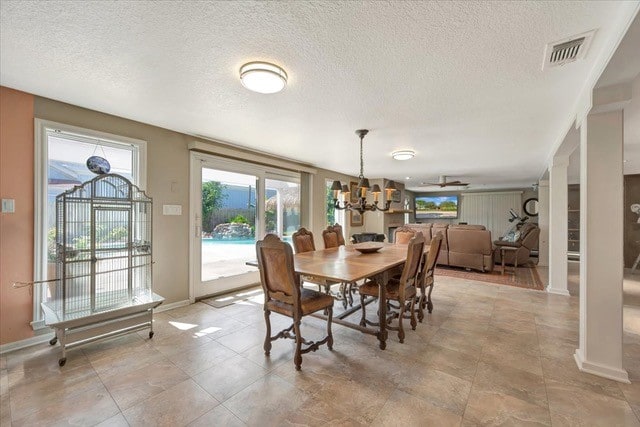 dining space with ceiling fan with notable chandelier and a textured ceiling