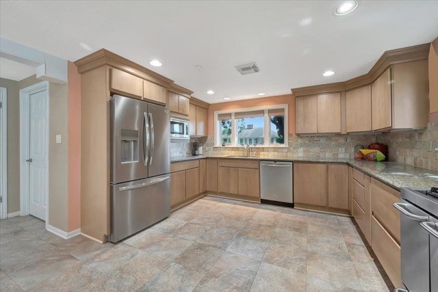 kitchen featuring appliances with stainless steel finishes, light brown cabinets, tasteful backsplash, and light stone counters