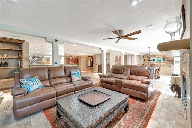 living room featuring ornate columns, ceiling fan, and a textured ceiling