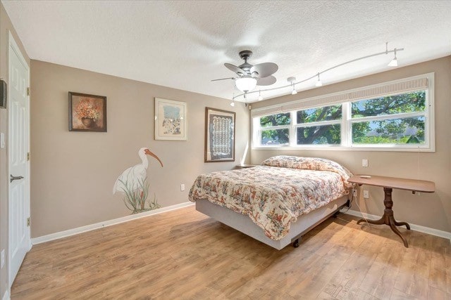 bedroom with a textured ceiling, light hardwood / wood-style floors, and ceiling fan