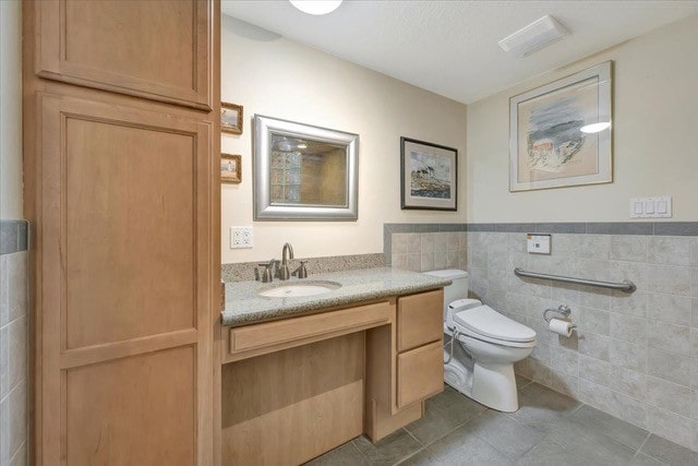 bathroom with tile patterned flooring, vanity, tile walls, and toilet