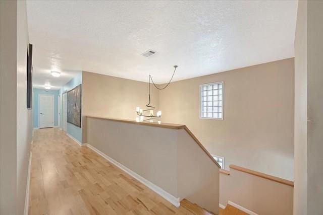 2601 Christopher Sq, Galveston, TX 77551 - hall with light wood-style flooring, an upstairs landing, baseboards, and a chandelier