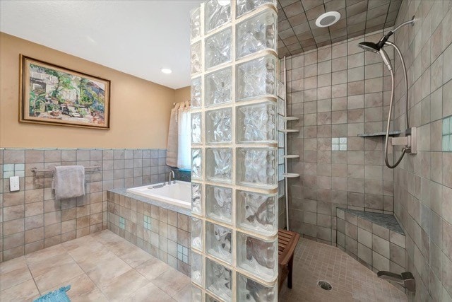 bathroom featuring tile patterned flooring, separate shower and tub, and tile walls