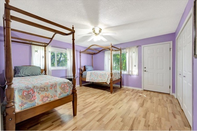 bedroom with multiple windows, ceiling fan, and light hardwood / wood-style flooring