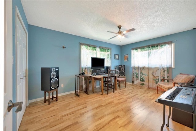 home office with a textured ceiling, light wood-type flooring, and ceiling fan