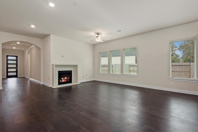 unfurnished living room featuring ceiling fan, dark hardwood / wood-style floors, and a healthy amount of sunlight