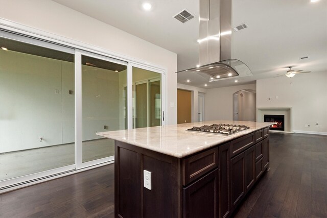 kitchen featuring stainless steel gas cooktop, a center island, ceiling fan, dark hardwood / wood-style floors, and dark brown cabinetry