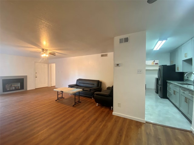 living room featuring ceiling fan, sink, and wood-type flooring