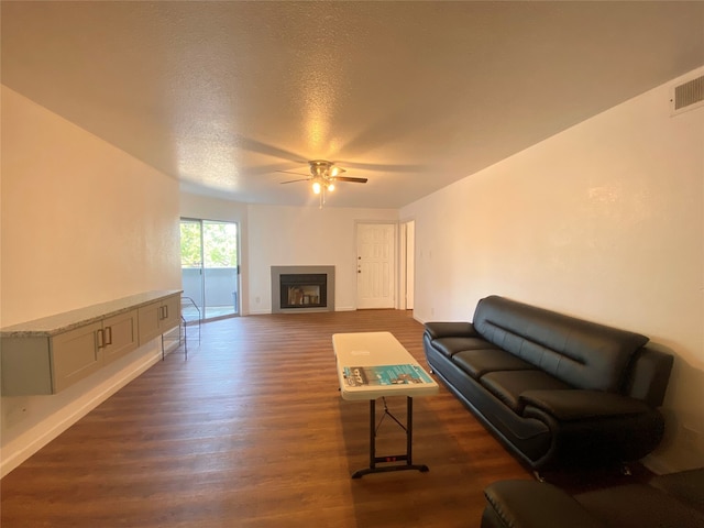 living room with ceiling fan, dark hardwood / wood-style flooring, and a textured ceiling