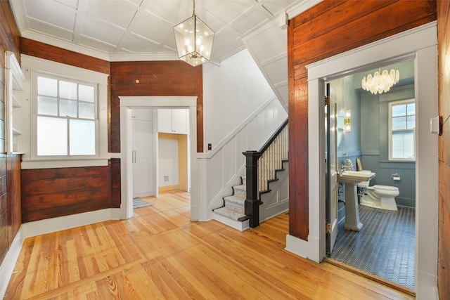 entryway featuring wooden walls, a chandelier, and light hardwood / wood-style floors