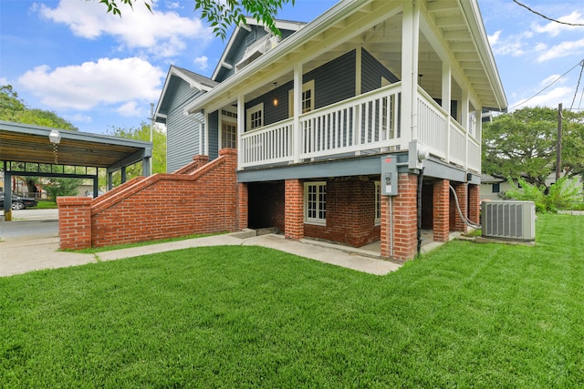 rear view of property with cooling unit, a carport, and a yard