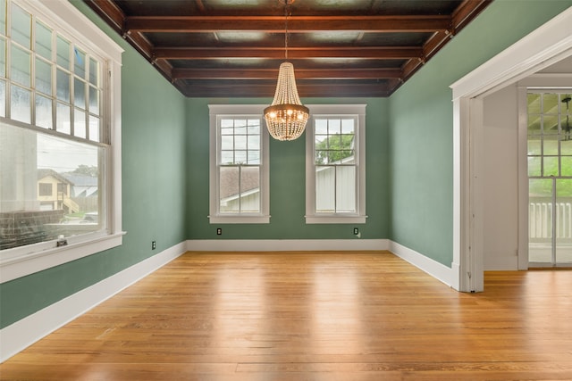 unfurnished dining area with an inviting chandelier, light hardwood / wood-style floors, and beam ceiling