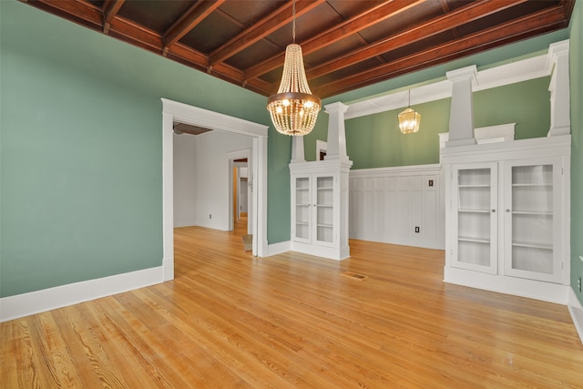 spare room featuring light hardwood / wood-style flooring, beamed ceiling, and an inviting chandelier