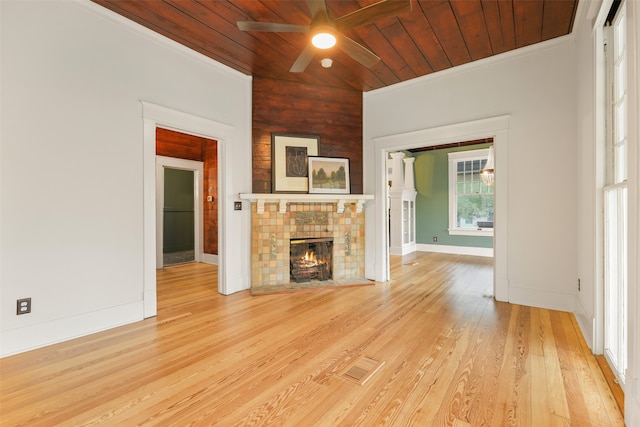 unfurnished living room featuring light hardwood / wood-style flooring, ceiling fan, a tile fireplace, and wooden ceiling