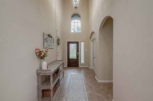 entrance foyer featuring a chandelier, a healthy amount of sunlight, and a high ceiling