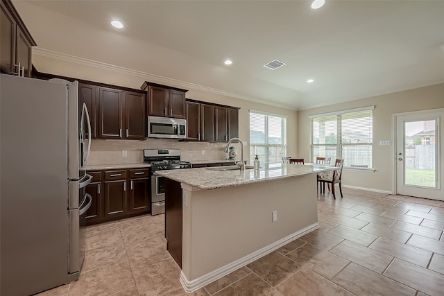 kitchen featuring appliances with stainless steel finishes, backsplash, a center island with sink, and a wealth of natural light