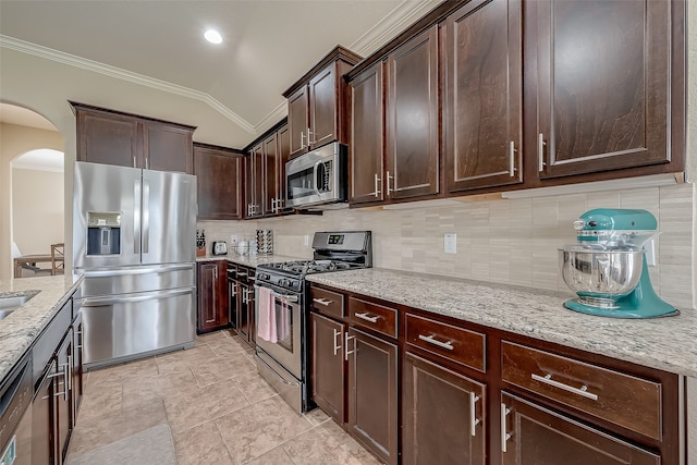 kitchen featuring lofted ceiling, decorative backsplash, appliances with stainless steel finishes, light stone counters, and dark brown cabinetry