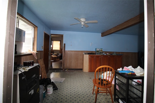 interior space featuring beamed ceiling, carpet floors, ceiling fan, and wooden walls