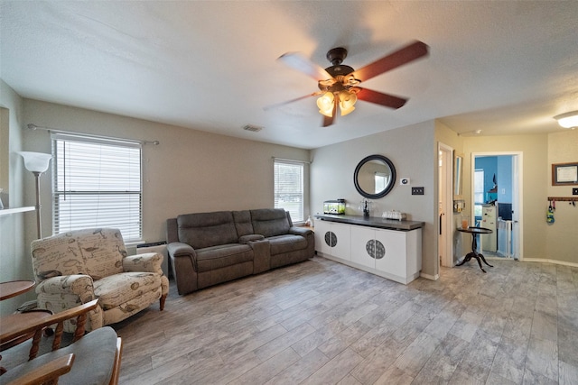 living room featuring a textured ceiling, a healthy amount of sunlight, ceiling fan, and light hardwood / wood-style floors