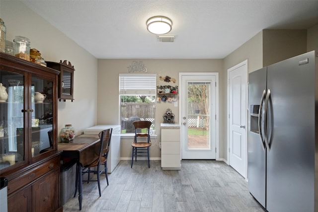 kitchen with light wood-type flooring and stainless steel refrigerator with ice dispenser