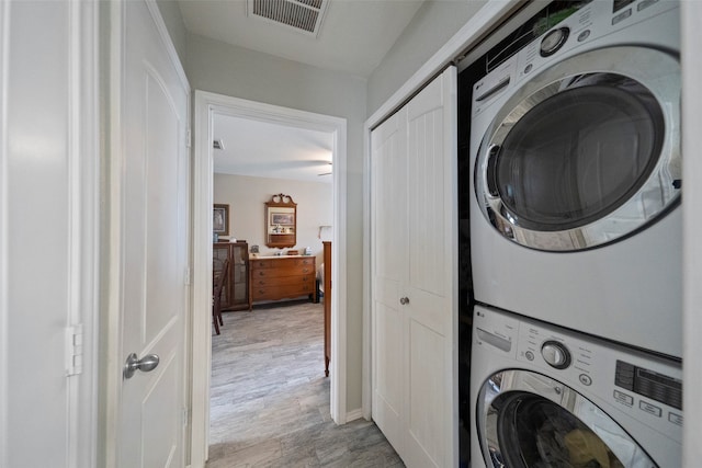 laundry room featuring light wood-type flooring and stacked washer and dryer