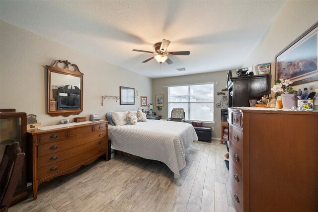 bedroom with a textured ceiling, ceiling fan, and light wood-type flooring