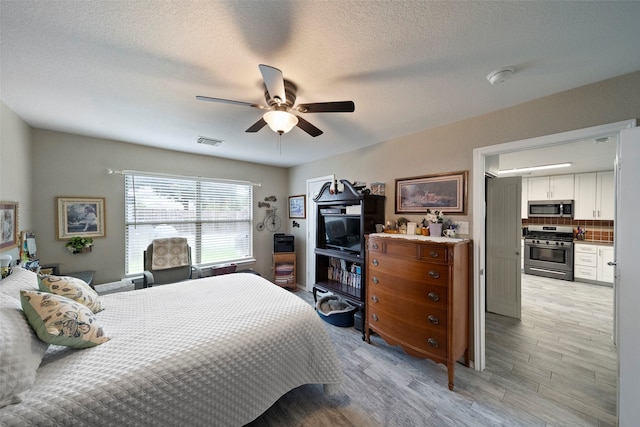 bedroom featuring light wood-type flooring, ceiling fan, and a textured ceiling