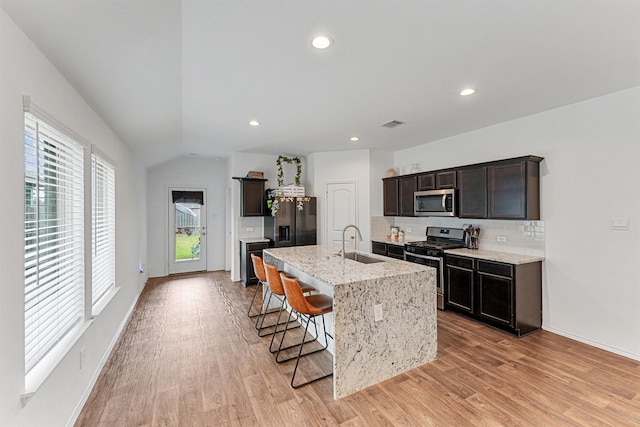 kitchen featuring light wood-type flooring, stainless steel appliances, sink, a breakfast bar area, and a kitchen island with sink