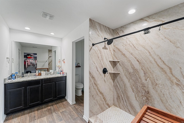 bathroom featuring vanity, toilet, a tile shower, and hardwood / wood-style floors