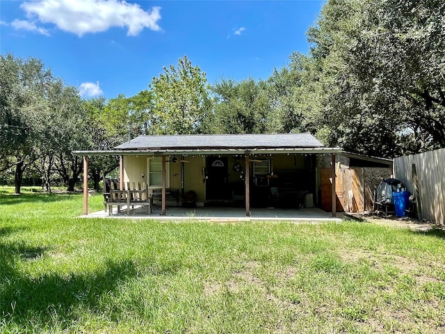 rear view of house with a storage unit, a lawn, and a patio area