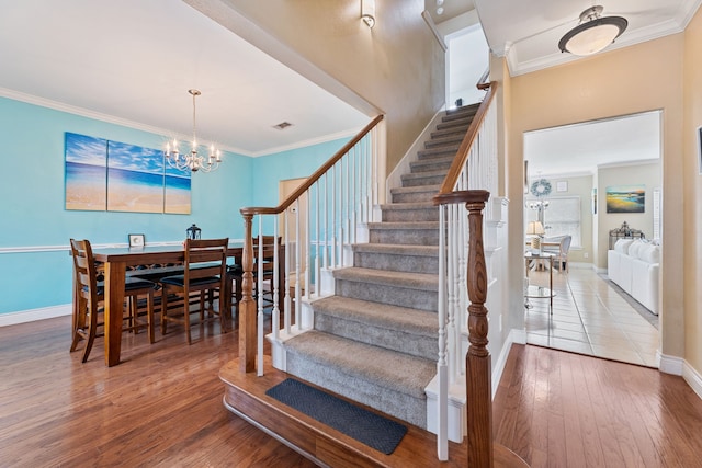 staircase with hardwood / wood-style flooring, a chandelier, and crown molding