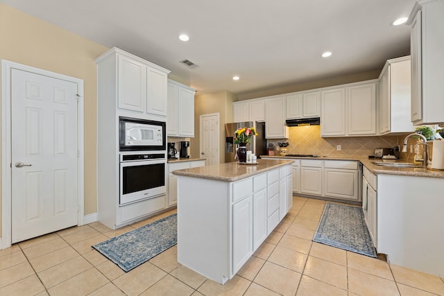 kitchen with a kitchen island, stainless steel appliances, sink, and white cabinets