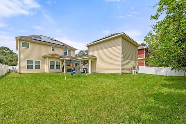 back of property with solar panels, a lawn, and central air condition unit