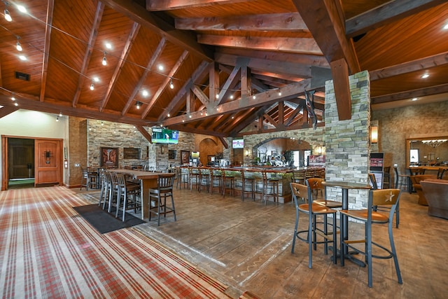 dining area featuring beamed ceiling, indoor bar, and high vaulted ceiling