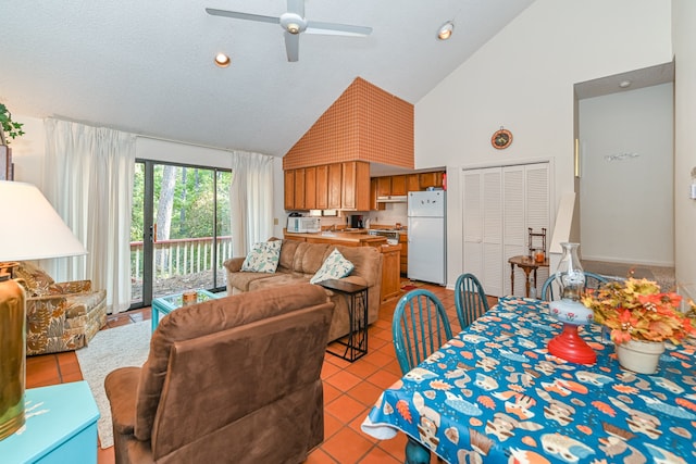 tiled dining space with high vaulted ceiling, ceiling fan, and a textured ceiling