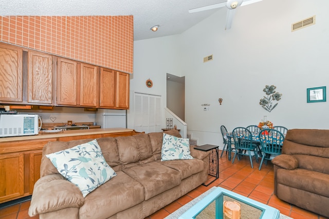 tiled living room featuring a textured ceiling, ceiling fan, and high vaulted ceiling