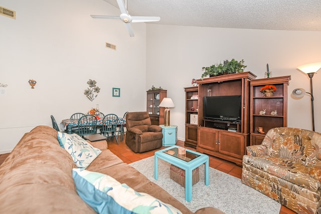 tiled living room featuring ceiling fan, a textured ceiling, and vaulted ceiling