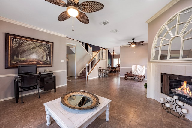 living room with ceiling fan with notable chandelier, ornamental molding, and a tile fireplace