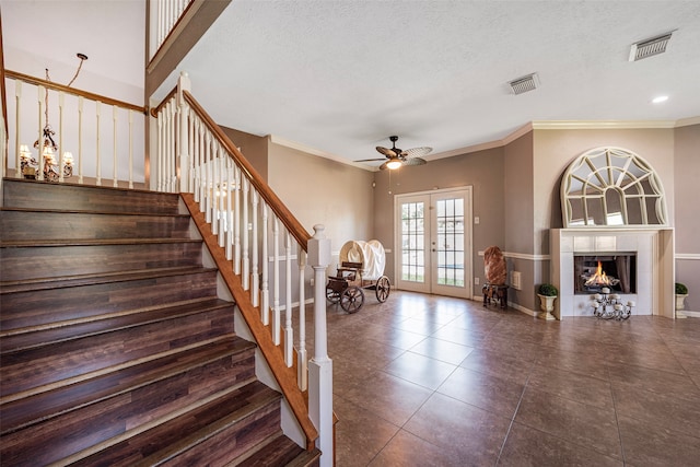 stairs with a fireplace, french doors, a textured ceiling, and ceiling fan