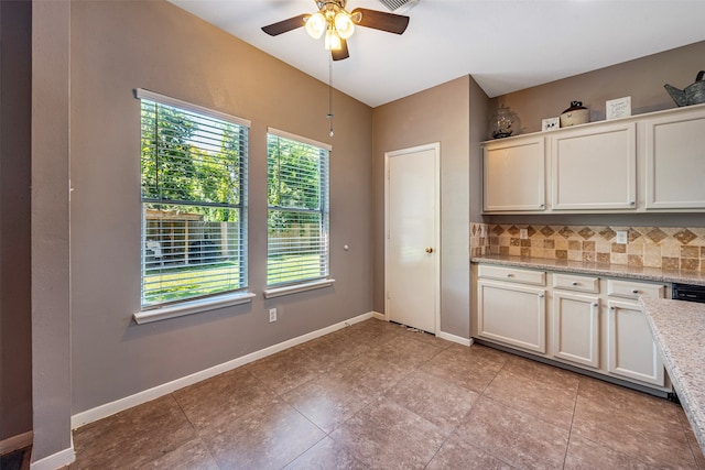 kitchen with ceiling fan, a wealth of natural light, light stone countertops, and tasteful backsplash