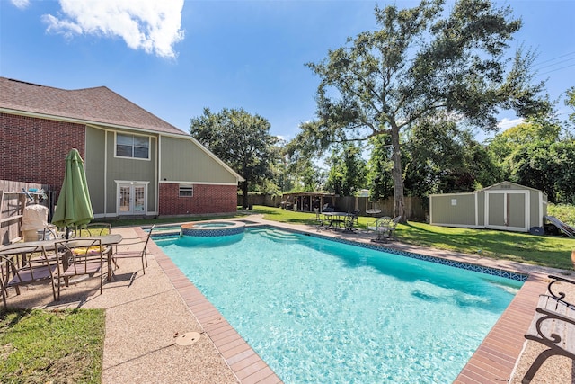 view of swimming pool featuring a patio area, a yard, an in ground hot tub, and a shed