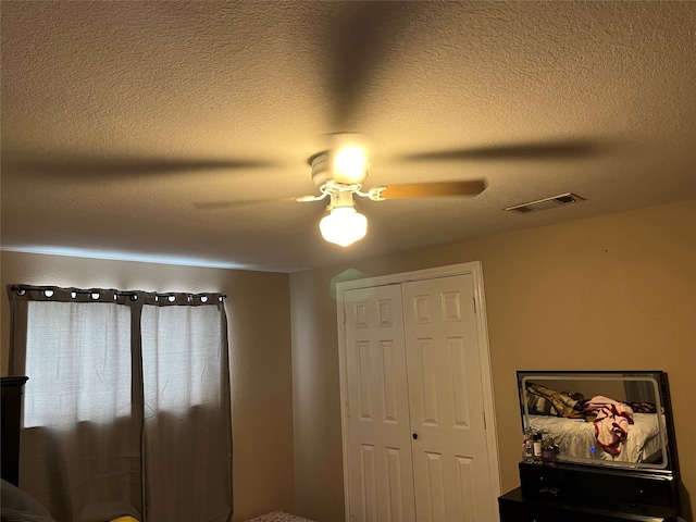 bedroom with a textured ceiling, ceiling fan, and a closet