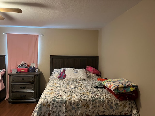 bedroom featuring ceiling fan, dark hardwood / wood-style flooring, and a textured ceiling