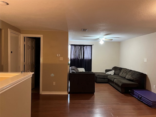 living room featuring ceiling fan, dark hardwood / wood-style flooring, and a textured ceiling