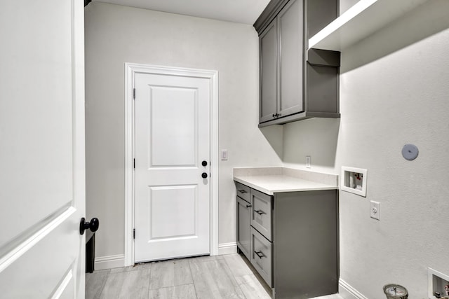 clothes washing area with cabinets, washer hookup, and light hardwood / wood-style floors