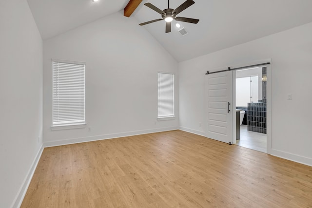 empty room featuring ceiling fan, beamed ceiling, high vaulted ceiling, light wood-type flooring, and a barn door